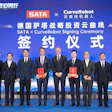Ten business executives in formal attire holding red documents at SATA and CurveRobot signing ceremony