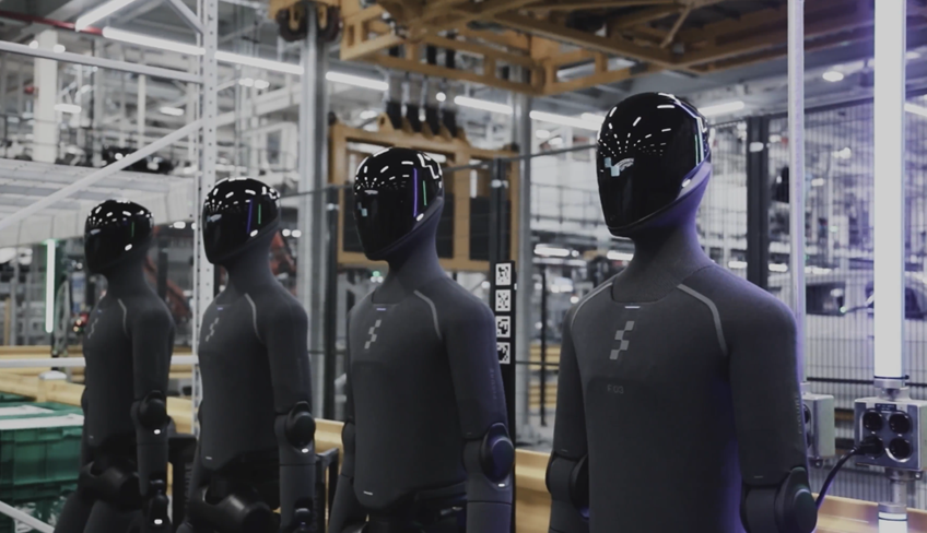 Row of black mannequins displayed in industrial warehouse setting with metal framework and equipment