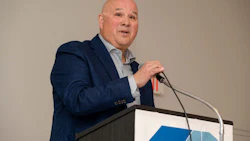 Professional man in navy blazer speaking at podium with microphone during corporate event