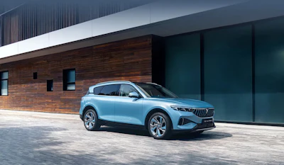 Light blue electric SUV parked in front of modern brick and glass building with contemporary architecture