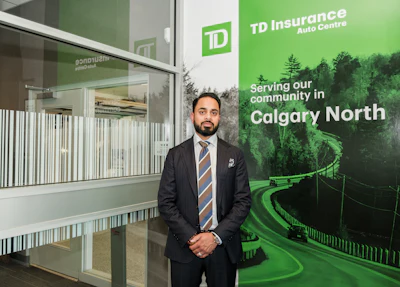 Professional man in dark suit standing in TD Insurance Auto Centre Calgary North location with green branded signage