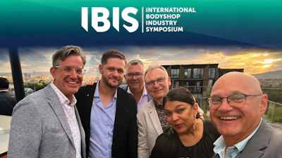 Six professionals posing together at sunset during the International Bodyshop Industry Symposium event