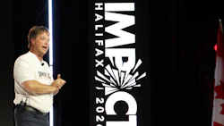 Speaker presenting at IMPACT Halfax 2026 conference with large event branding signage and blue accent lighting