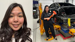 Professional woman in automotive repair facility holding hydraulic jack near damaged vehicle