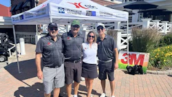 Four team members in branded apparel stand together at a 3M and Platinum Automotive promotional tent during an outdoor event.