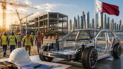 Electric vehicle chassis displayed at construction site with workers and Dubai skyline in background