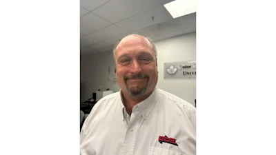 Professional headshot of a smiling man in white shirt at an indoor office setting