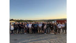 Large group of professionals standing together on a rooftop during sunset with mountains visible in the background