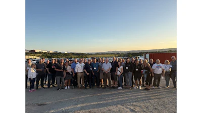 Large group of professionals standing together on a rooftop during sunset with mountains visible in the background