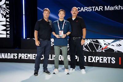 Three men standing on stage at CARSTAR Markham event, with center person holding an award