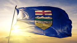 Alberta provincial flag waving at sunset with coat of arms emblem featuring mountains and wheat