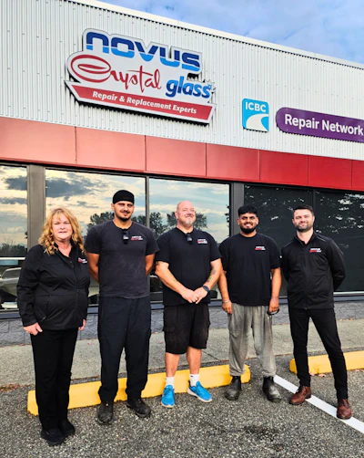 Five team members in black uniforms stand outside Nevus Weld Glass repair shop storefront