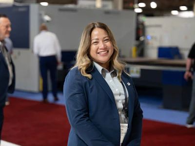 Professional woman in navy blazer smiling at conference or trade show event