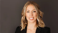 Professional headshot of a woman with shoulder-length blonde hair smiling against a gray background
