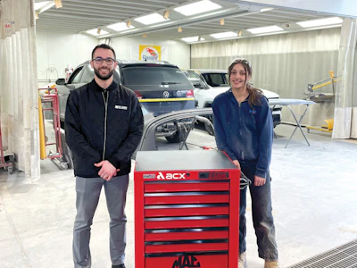 Two automotive technicians stand beside a red ACX toolbox in a professional workshop garage