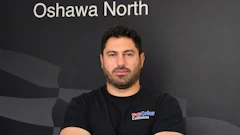 Professional man in ProColor Collision branded shirt posing against company backdrop