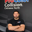 Professional man in ProColor Collision branded shirt posing against company backdrop
