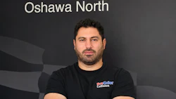 Professional man in ProColor Collision branded shirt posing against company backdrop