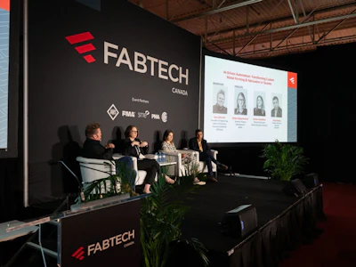 Panel discussion at FABTECH Canada conference with four speakers seated on stage before branded backdrop and projection screen