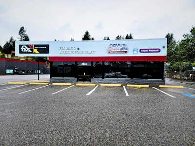 Auto repair shop storefront with blue and white signage displaying Collision Center, Novus, and Repair Network branding