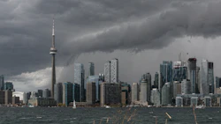 Toronto skyline with CN Tower under dramatic storm clouds, viewed across Lake Ontario