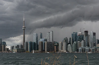 Toronto skyline with CN Tower under dramatic storm clouds, viewed across Lake Ontario
