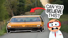 Vintage orange car on rural road with animated character saying 'Can you believe this?' in speech bubble