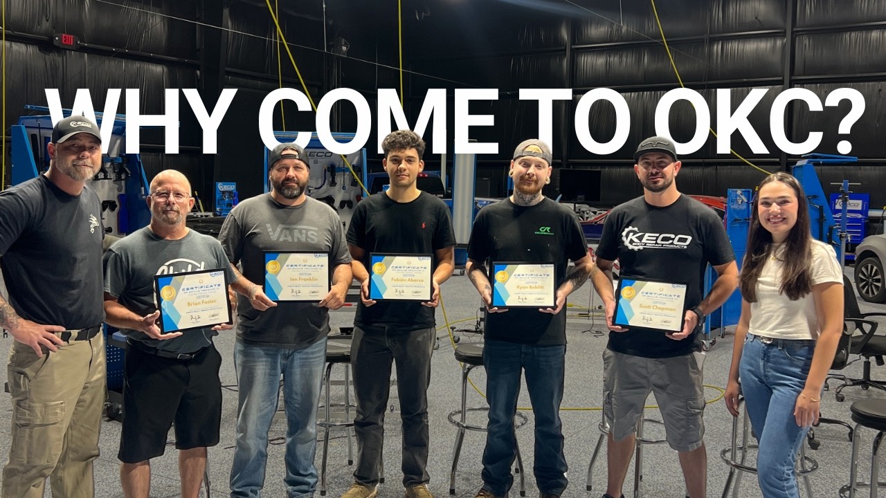 Group of eight people holding certificates in an industrial garage setting with text 'Why Come to OKC?'