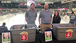 Three people hold collection bins with promotional materials at an ice hockey arena