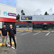 Auto glass repair shop storefront with five team members in black uniforms standing in front of the building entrance