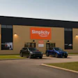 Simplicity car wash storefront with tan brick exterior, black trim, and orange signage, displaying three parked vehicles in front