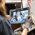 Technician holding rugged tablet displaying industrial equipment footage on job site