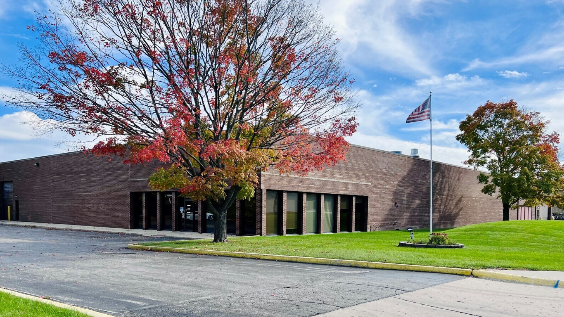 Modern brick building with red autumn foliage and American flag on manicured grounds
