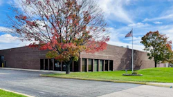 Modern brick building with red autumn foliage and American flag on manicured grounds