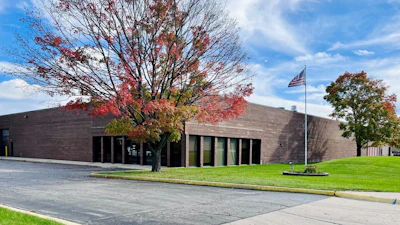 Modern brick building with red autumn foliage and American flag on manicured grounds