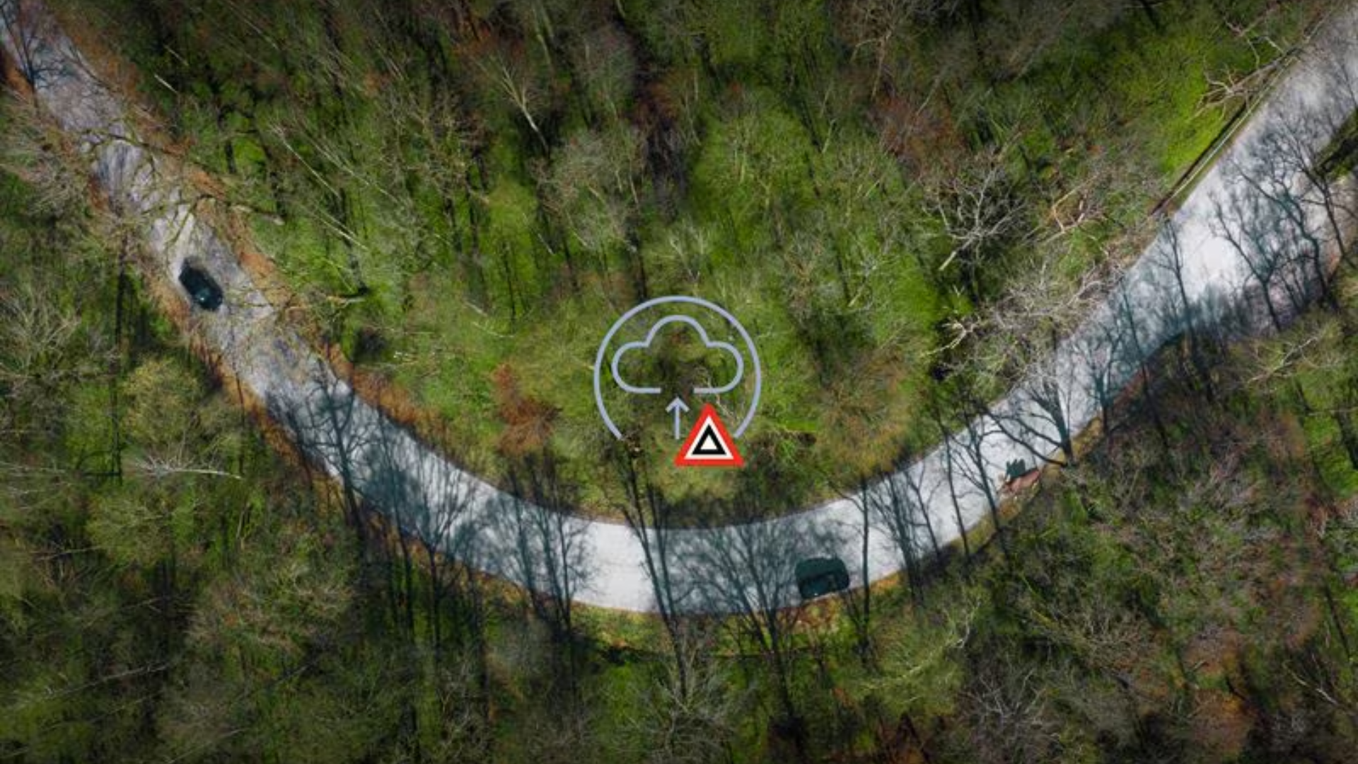 Aerial view of winding forest road with cloud and warning triangle icons overlay