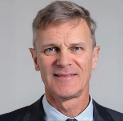 Professional headshot of a middle-aged man wearing a dark blazer and light blue shirt