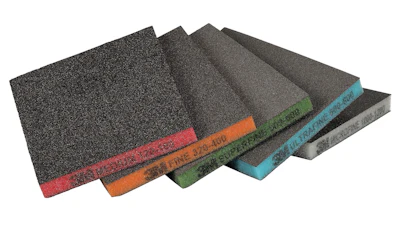 Assorted sandpaper sheets fanned in display showing different grit levels with colored edge labels