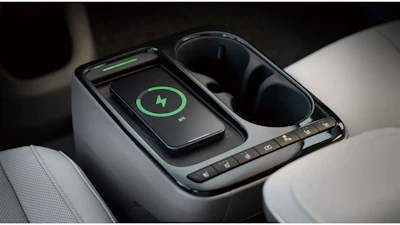 Smartphone with green lightning bolt charging icon displayed on wireless charging pad in car console