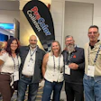 Five professionals wearing lanyards pose together at a corporate event with ProCool Coilsort branded signage