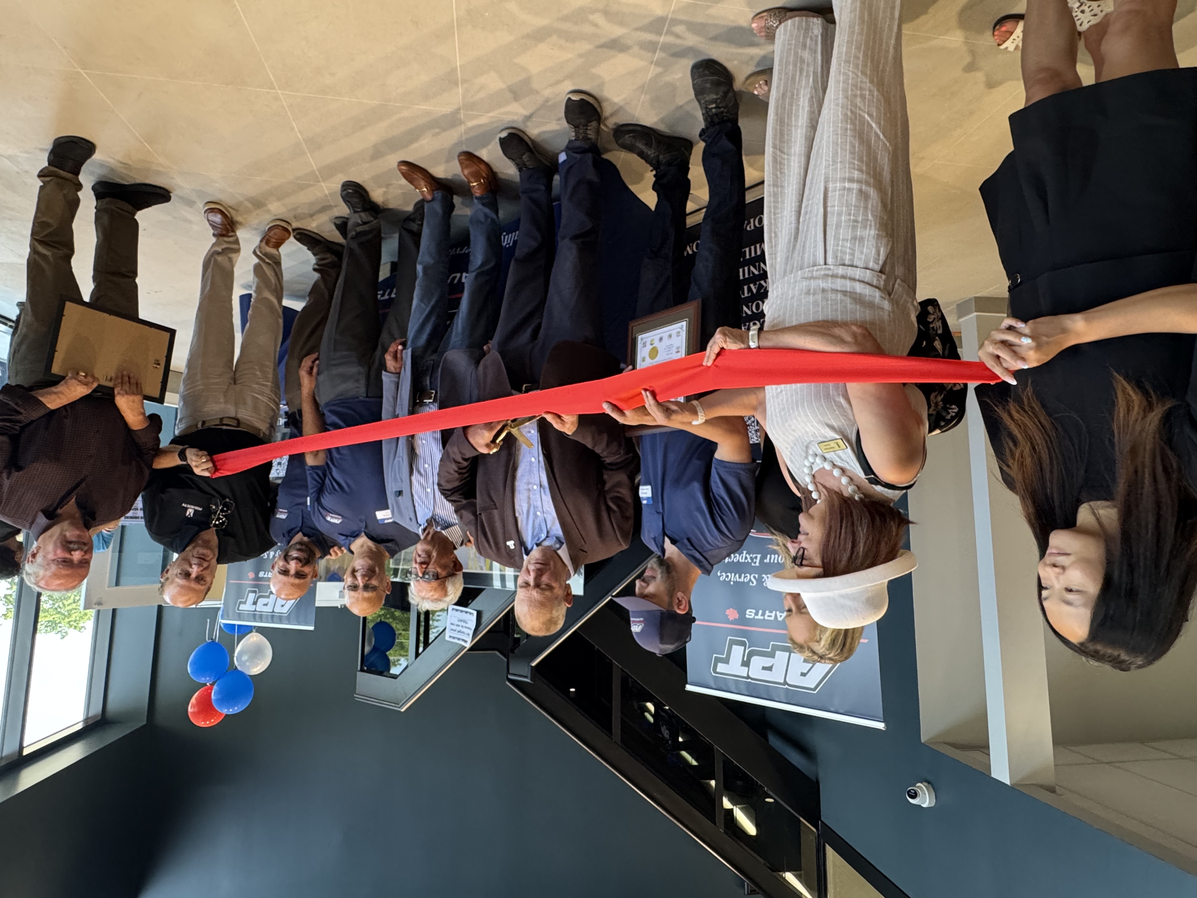 Group of professionals and community members participating in ribbon-cutting ceremony at APT facility opening