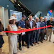 Group of professionals and community members participating in ribbon-cutting ceremony at APT facility opening