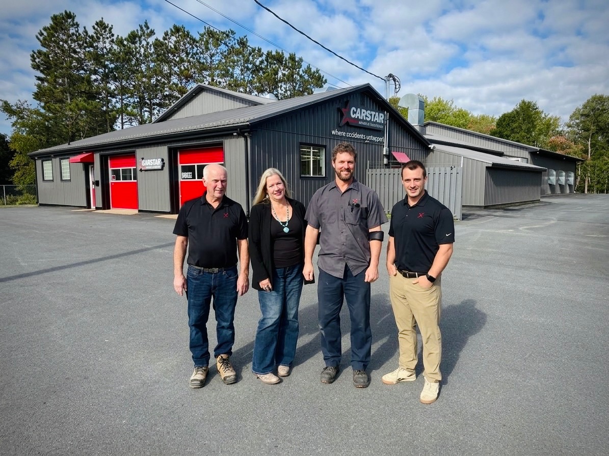 Four employees standing outside Capstan automotive service facility with red garage doors