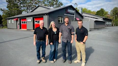 Four employees standing outside Capstan automotive service facility with red garage doors