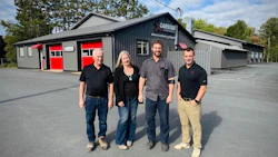 Four employees standing outside Capstan automotive service facility with red garage doors