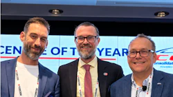 Three professionals in business attire at a corporate event with conference badges and award recognition display