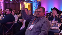 Professional attendees at a formal dinner event with purple ambient lighting and stage setup in background