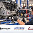 Technician using 3D scanning camera to inspect vehicle frame in automotive manufacturing facility