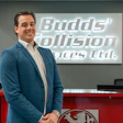 Professional man in blue blazer standing in modern office with Budds' Collision Services Ltd. signage