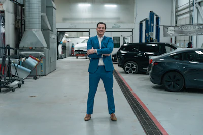 Professional man in blue suit standing confidently in modern automotive service facility